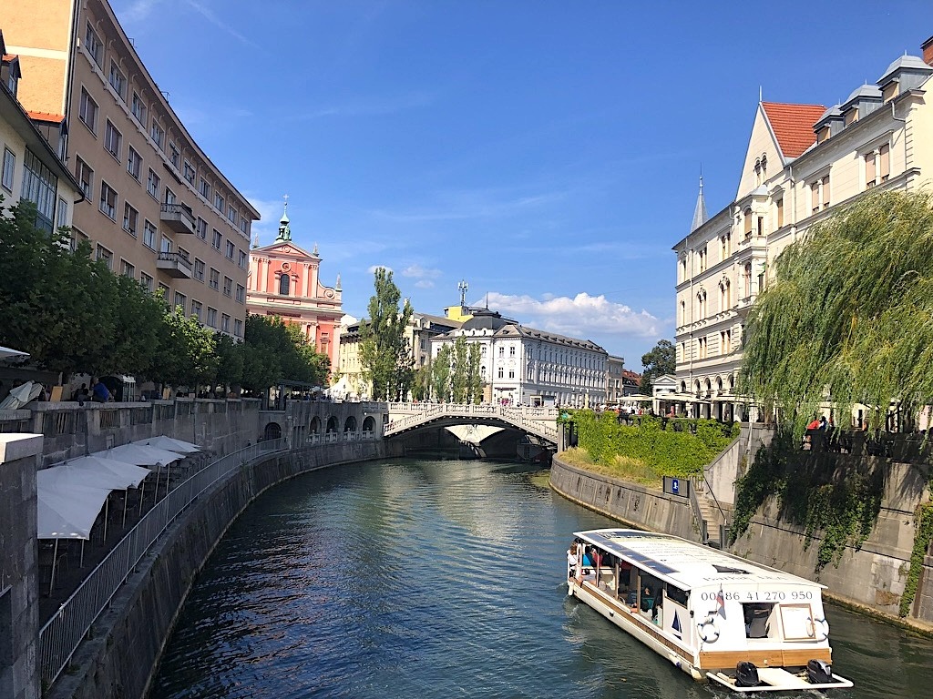 Canale del fiume Ljubljanica nel centro storico di Lubiana con battello turistico e ponte