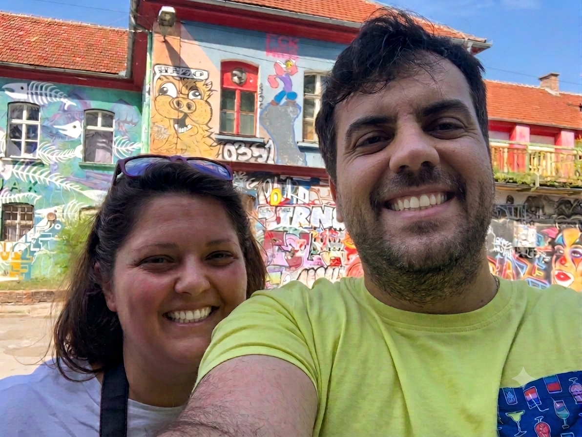 Veronica e Andrea sorridenti davanti ai murales colorati del quartiere di Metelkova a Lubiana