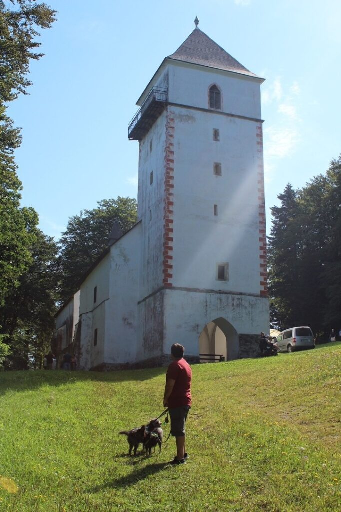 Andrea con Ciocia e Kiko al guinzaglio nel prato davanti alla chiesetta del Pohorje