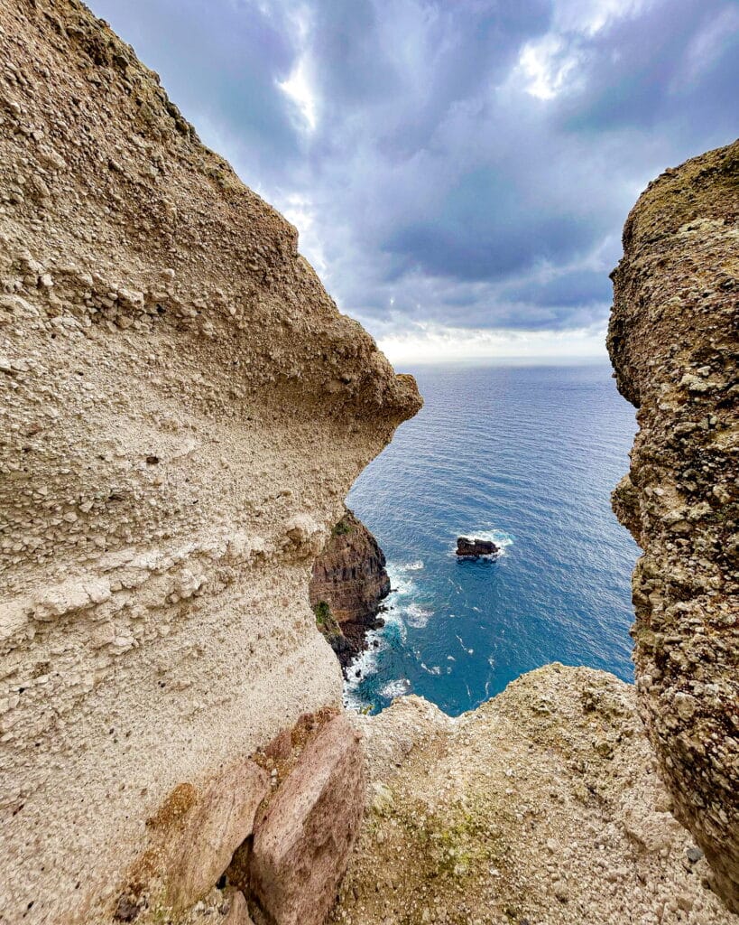 Scorcio panoramico sul mare e le rocce di tufo a Ischia durante un'escursione di trekking."