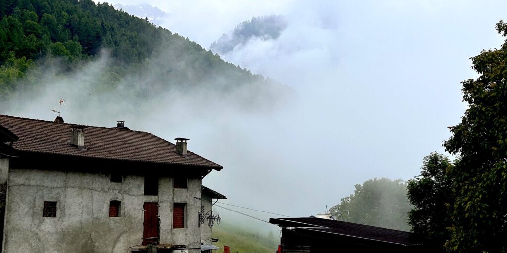 Nebbia estiva che avvolge le case del borgo di Aprica in Valtellina