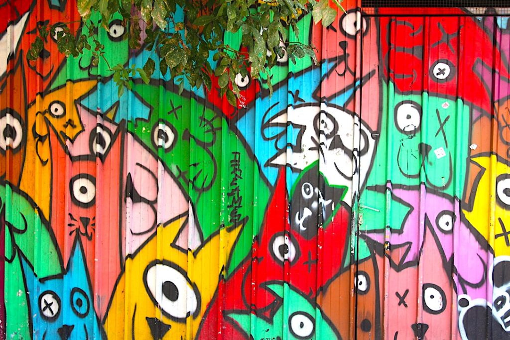 Muro rosso dipinto con personaggi e simboli, Metelkova