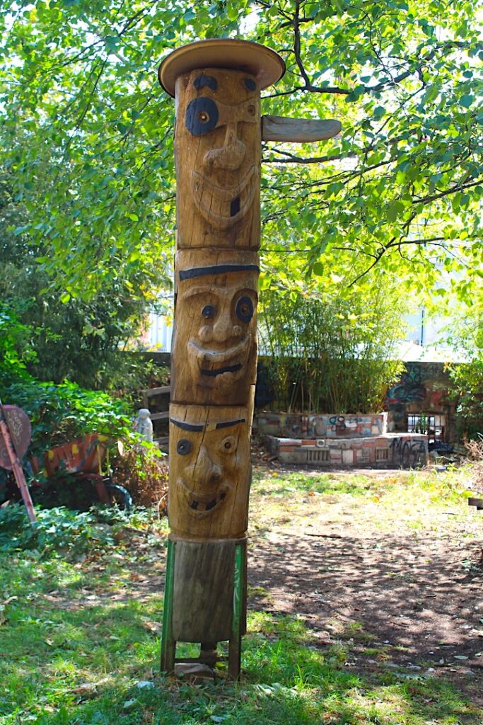 Totem di legno scolpito con tre volti, quartiere Metelkova, Lubiana