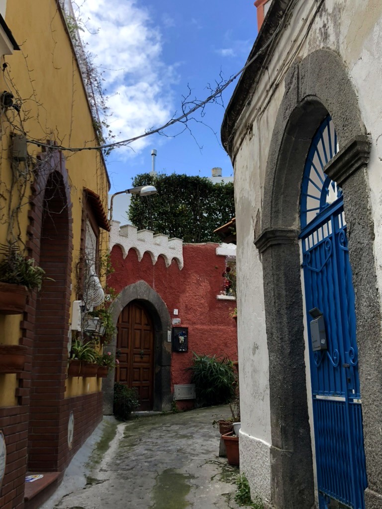 Vicolo colorato nel centro storico di Forio con cancello blu in ferro battuto